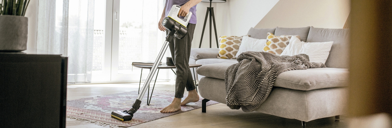 A person cleaning a carpet floor with a vacuum cleaner