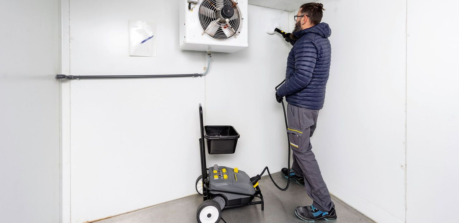 Steam cleaning cold storage Man cleaning the air conditioning of cold storage with vacuum cleaner.