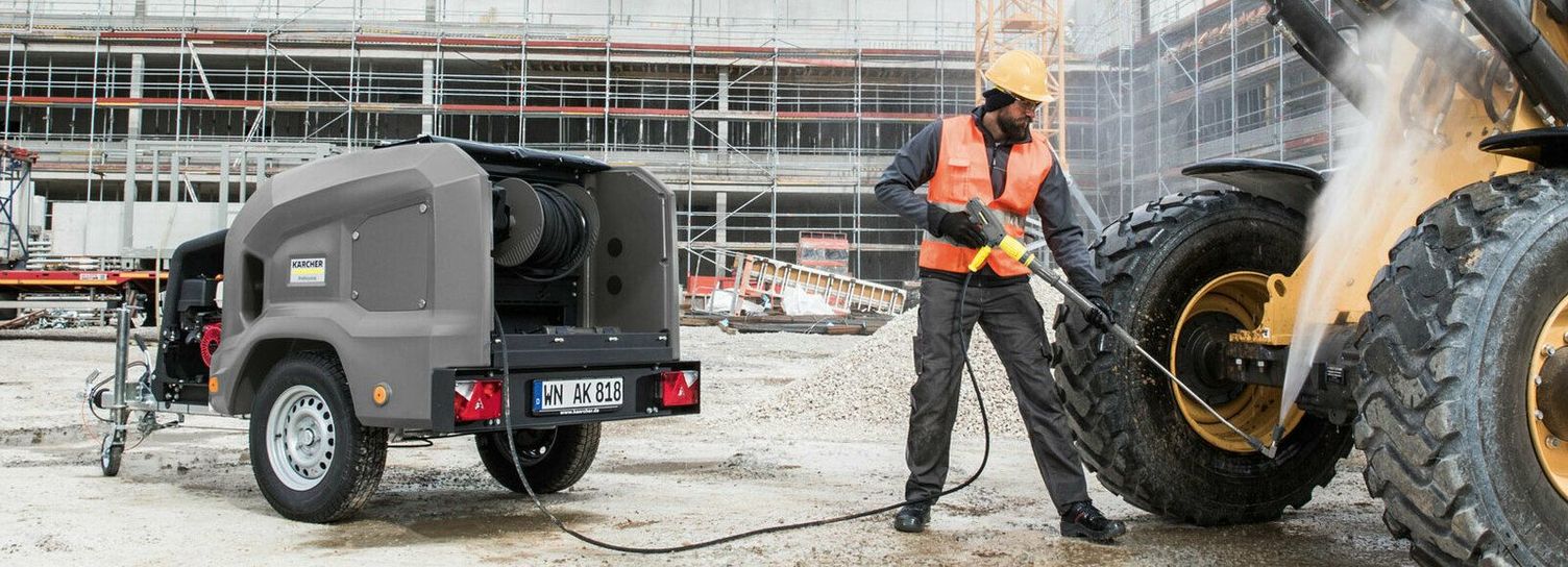 Using the HDS trailer for construction equipment cleaning A person cleans an excavator with the help of a Kärcher HDS Trailer