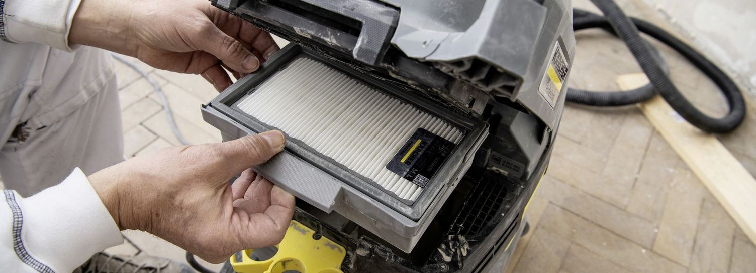 A person changes a filter of a vacuum cleaner
