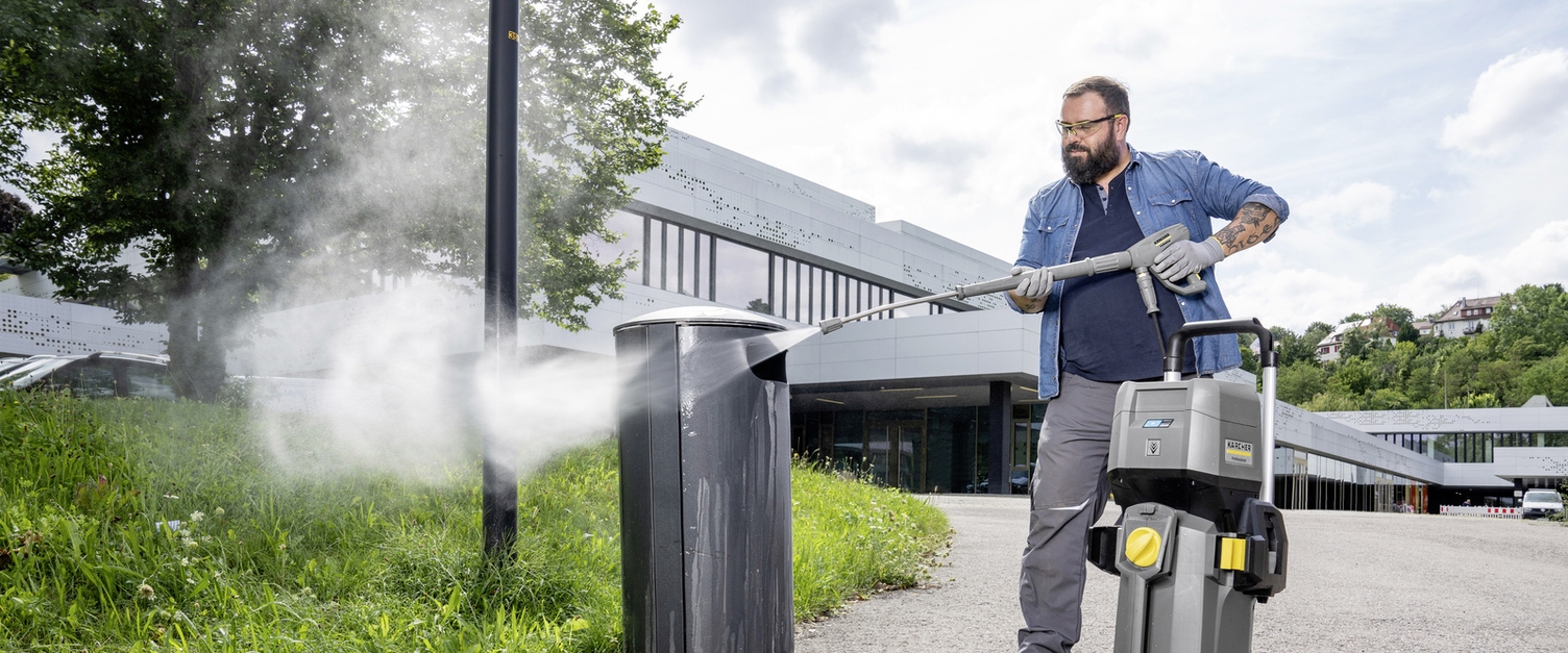 A person cleaning a waste bin with a Kärcher high-pressure cleaner