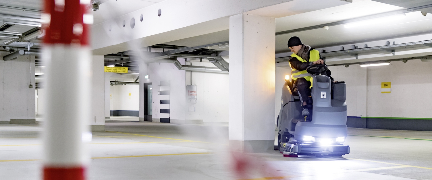 a person operating a vacuum sweeper in a car park