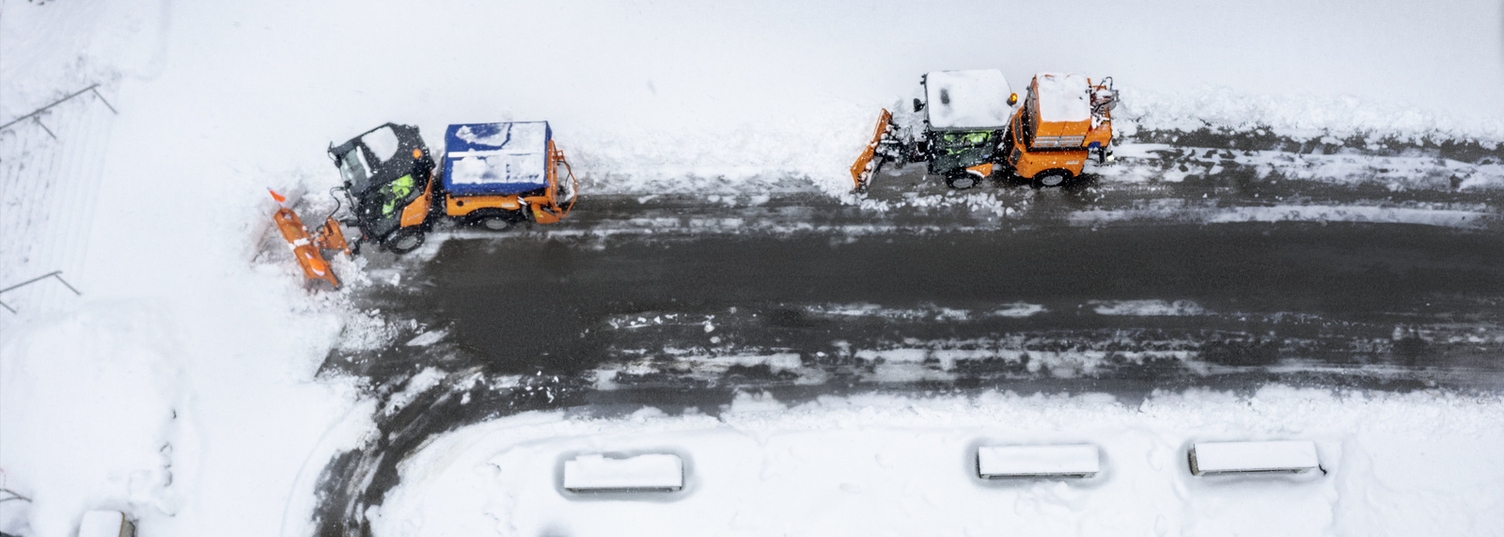 Two Kärcher snow vehicles clearing a snow-covered road
