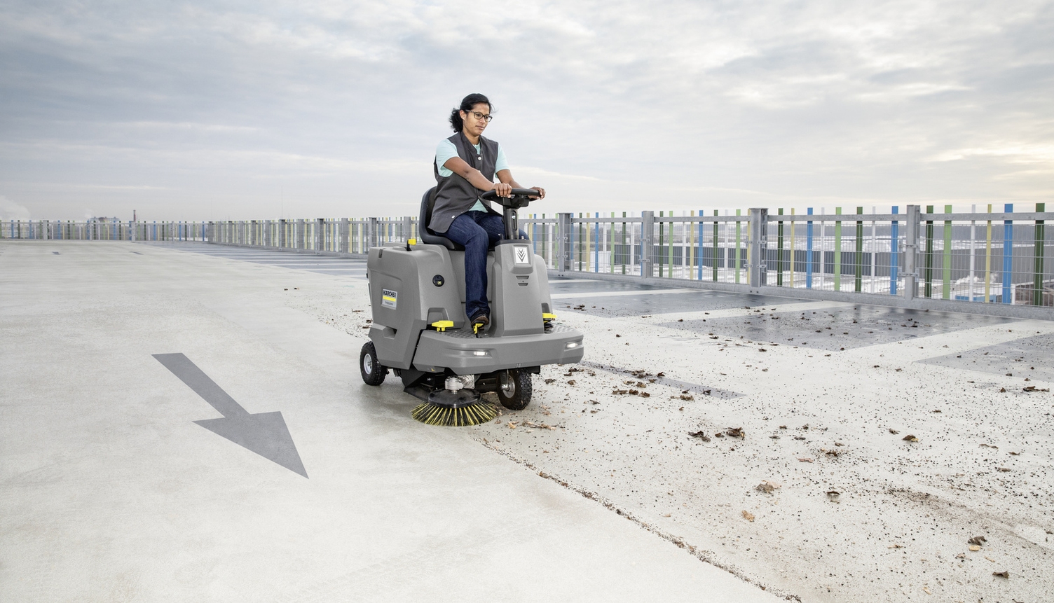 a cleaning professional cleaning a parking deck with a vacuum sweeper