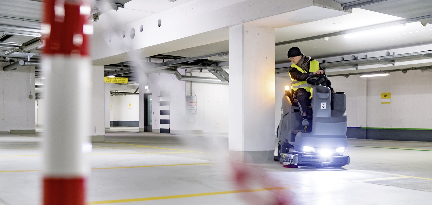 A person operating a ride-on sweeper