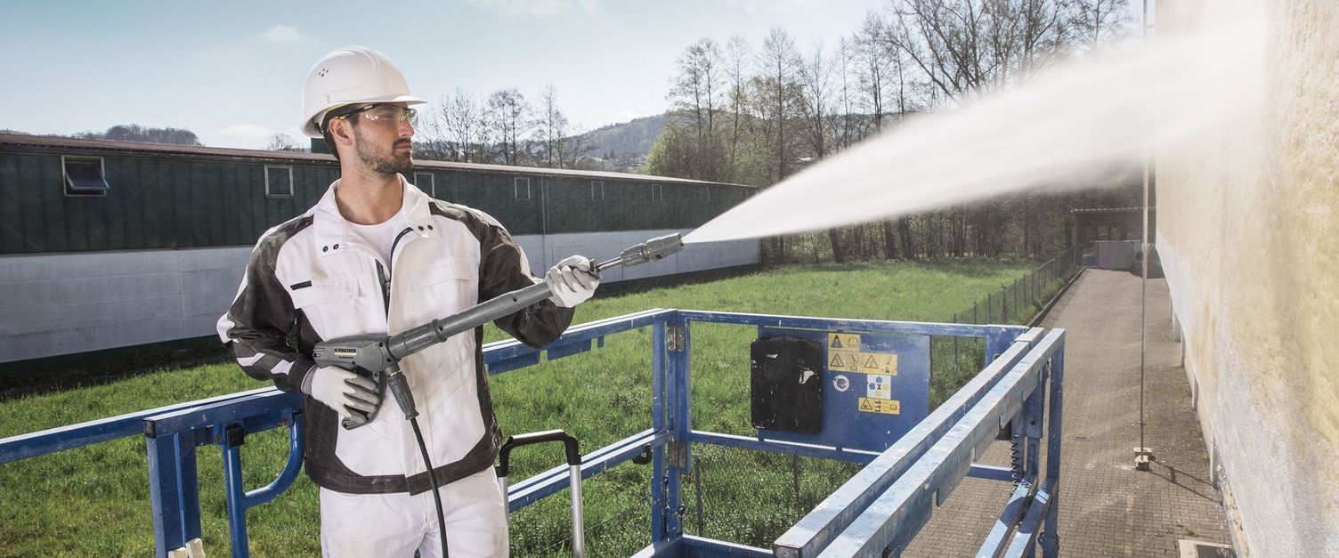 Facade cleaning A person on a hoist uses a Kärcher High-Pressure Cleaner for facade cleaning