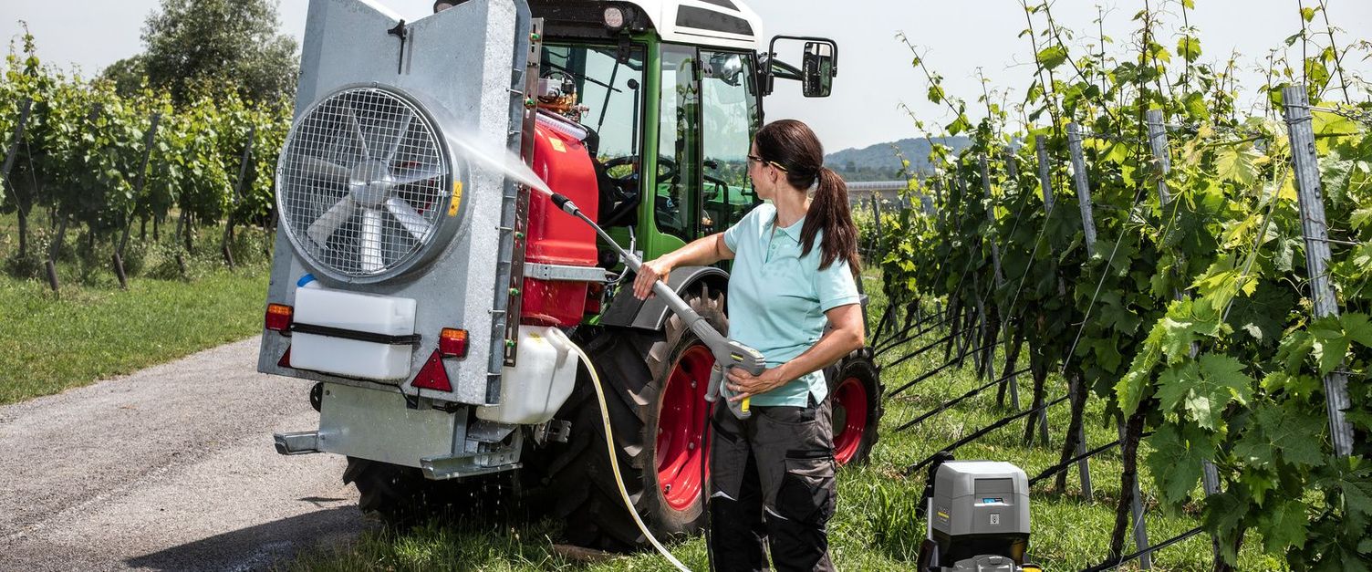 A woman cleans her tractor/harvesting machine with the Kärcher high-pressure cleaner