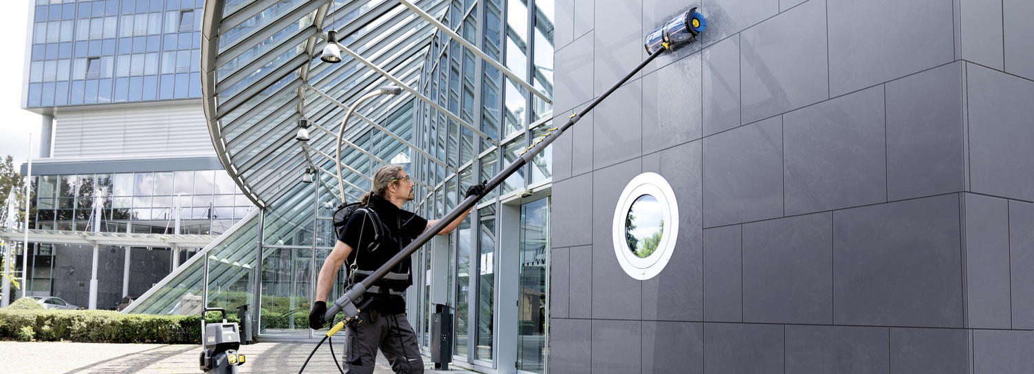 A person cleaning the facade of a hotel with a high-pressure cleaner
