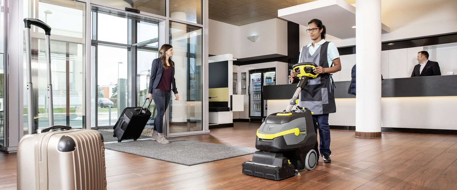 A person cleaning the floor with a Kärcher carpet cleaning machine