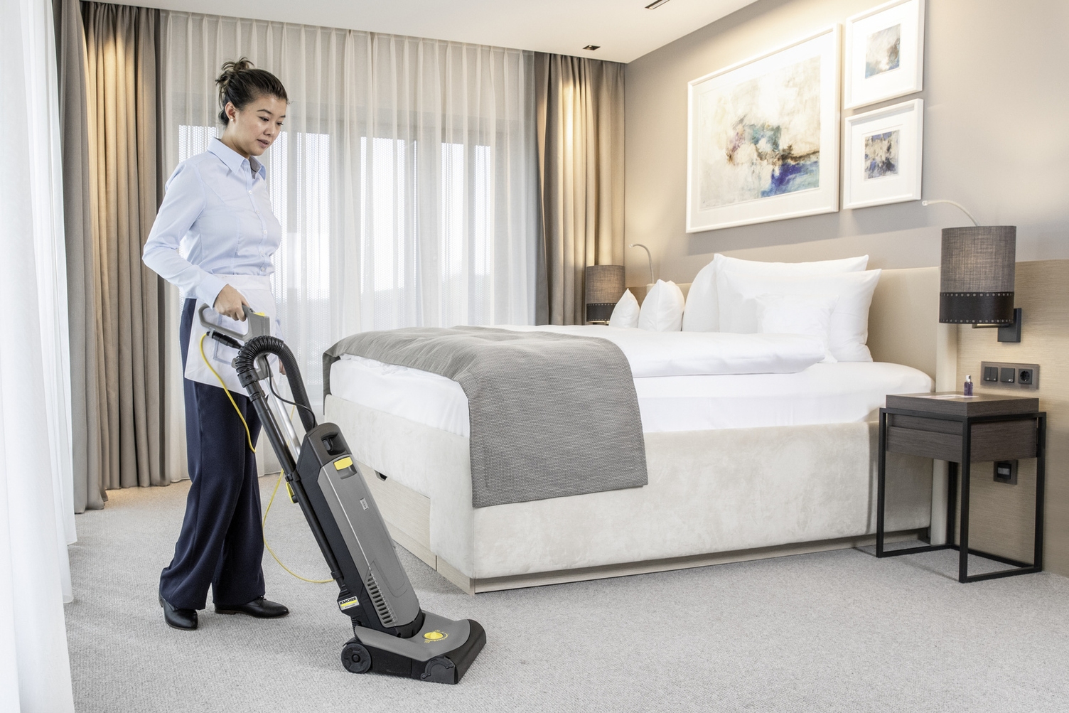 A person walks through the hotel room with a vacuum cleaner