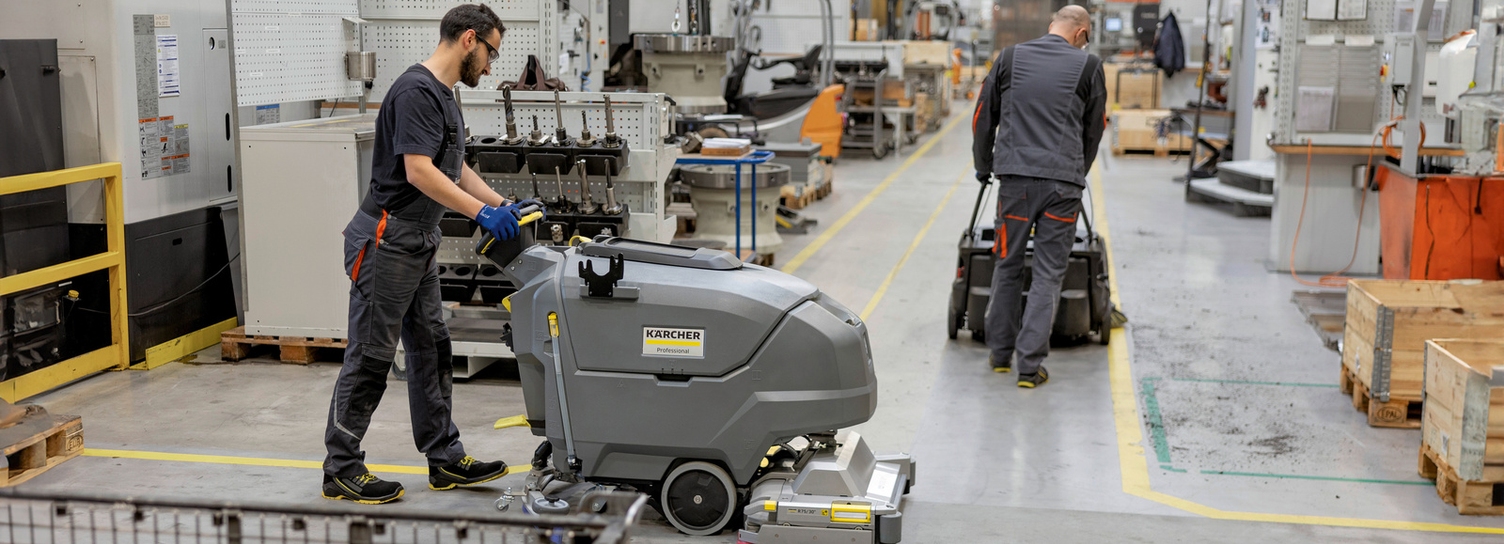 Two people clean the floor in a production facility