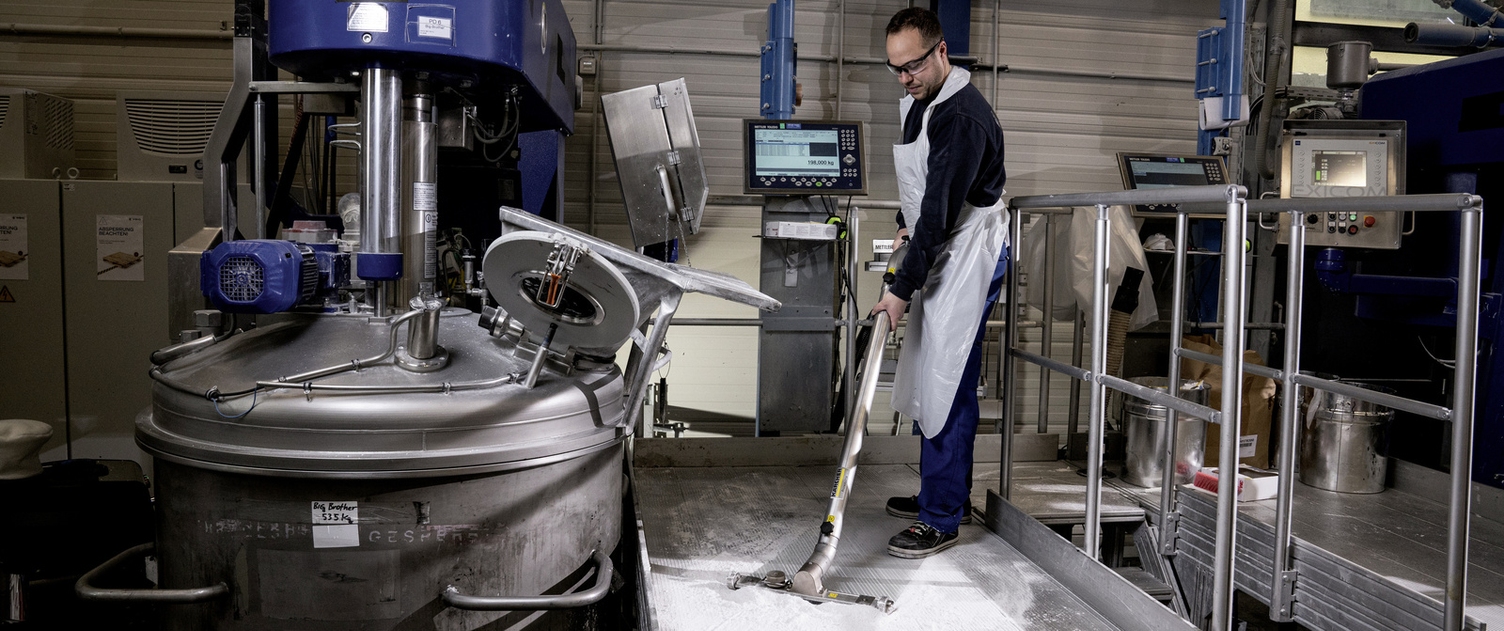 A man vacuums dirt particles in the production area