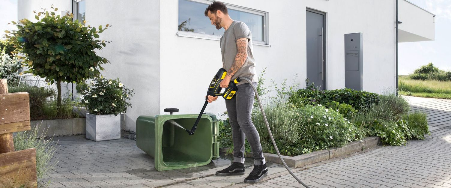 A man cleans a bin with a Kärcher medium pressure washer