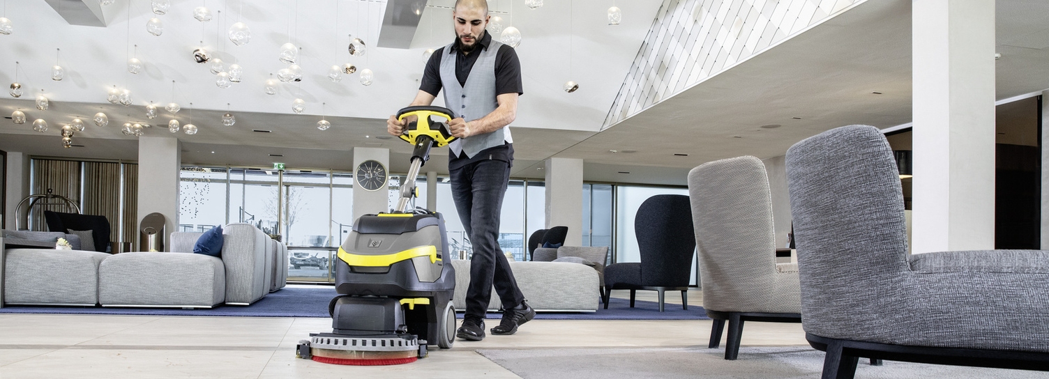 A man cleaning a hotel area with a scrubber dryer