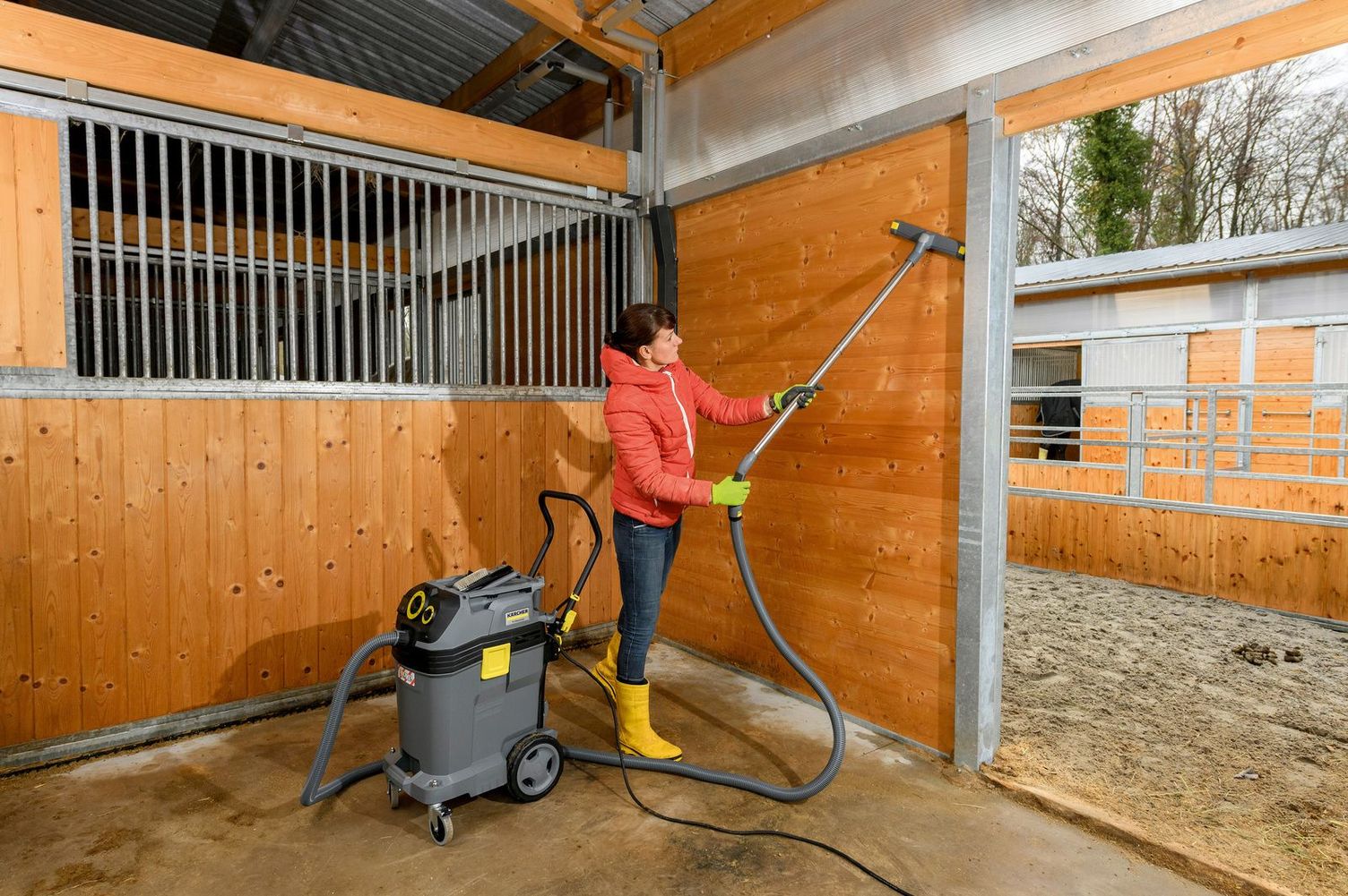 A woman cleans the walls of a horse stable