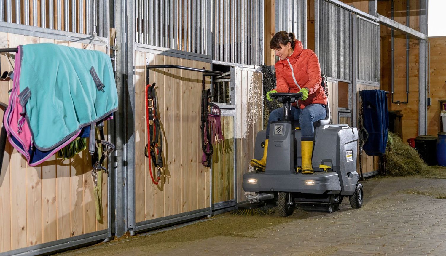 Cleaning the horse stable with a sweeper ride-on