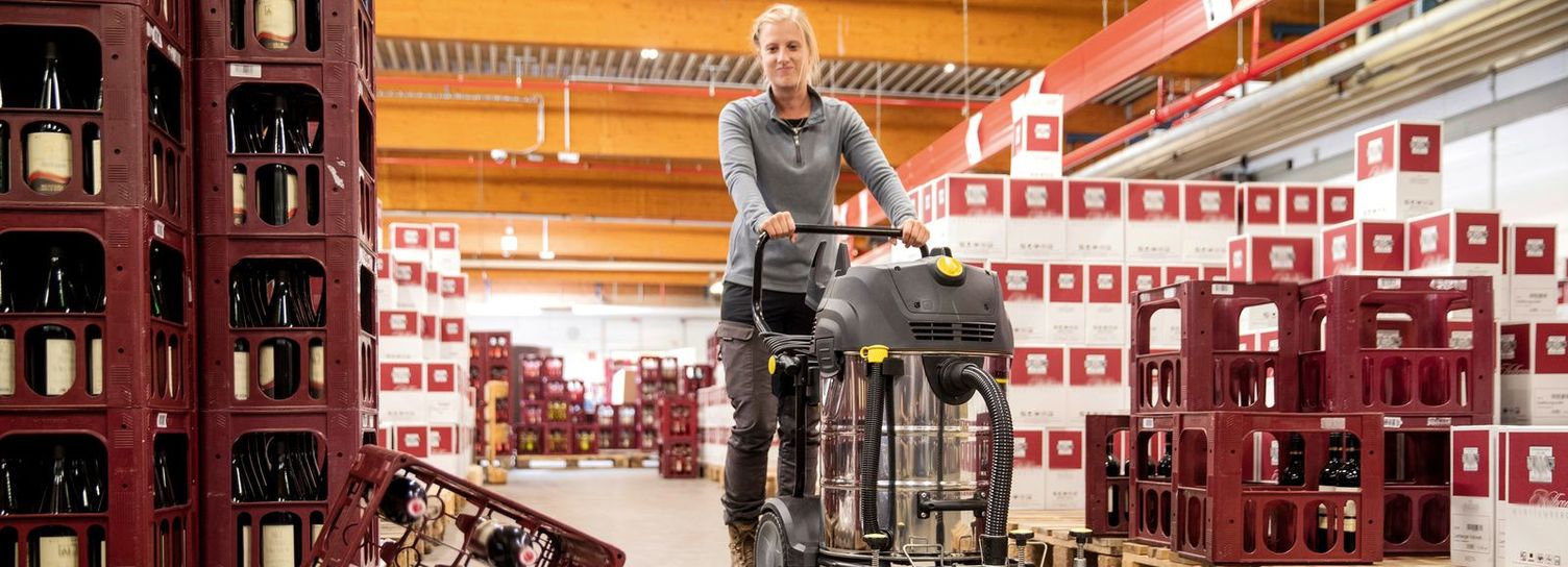 A woman is cleaning the wine warehouse and notices an overturned crate and broken wine bottles