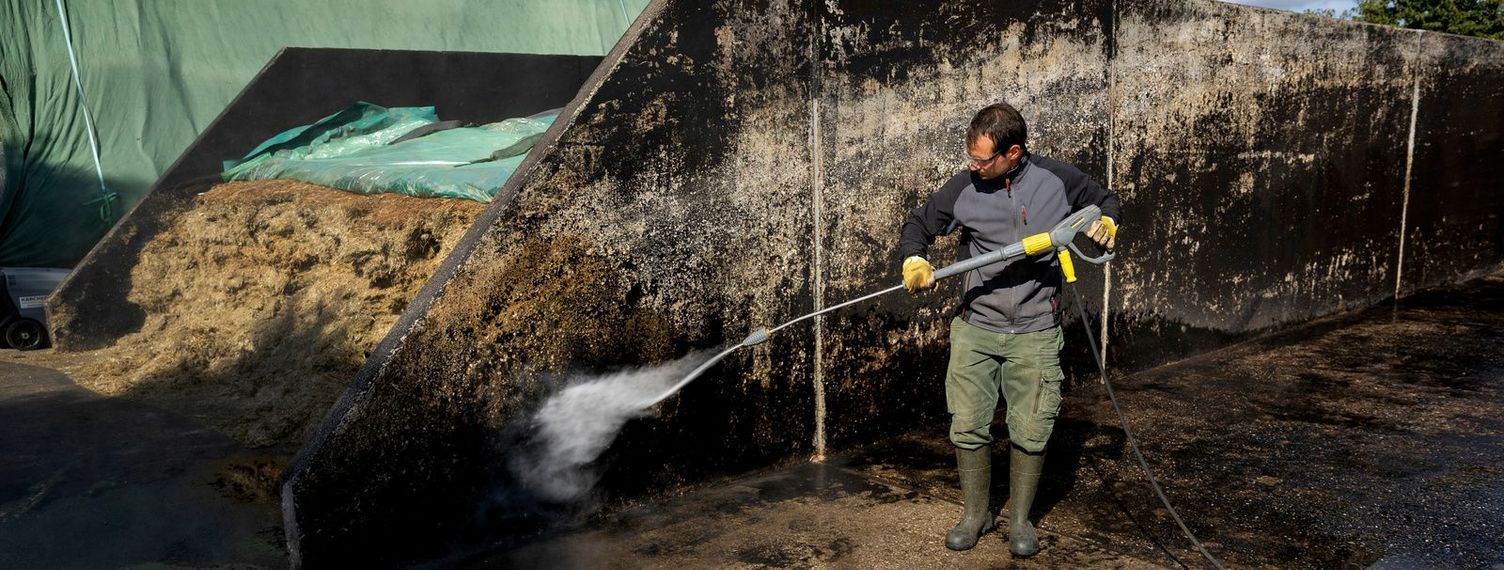 Cleaning the walls of a mobile silo with a high-pressure cleaner A man cleaning the wall of a flat silo with a high-pressure cleaner