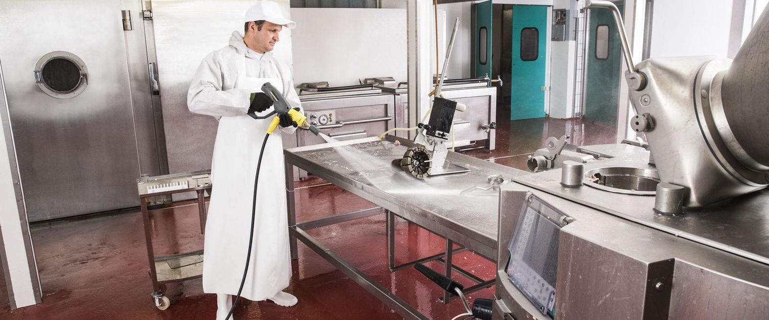 A man in white work clothes sprays the work area using a Kärcher device