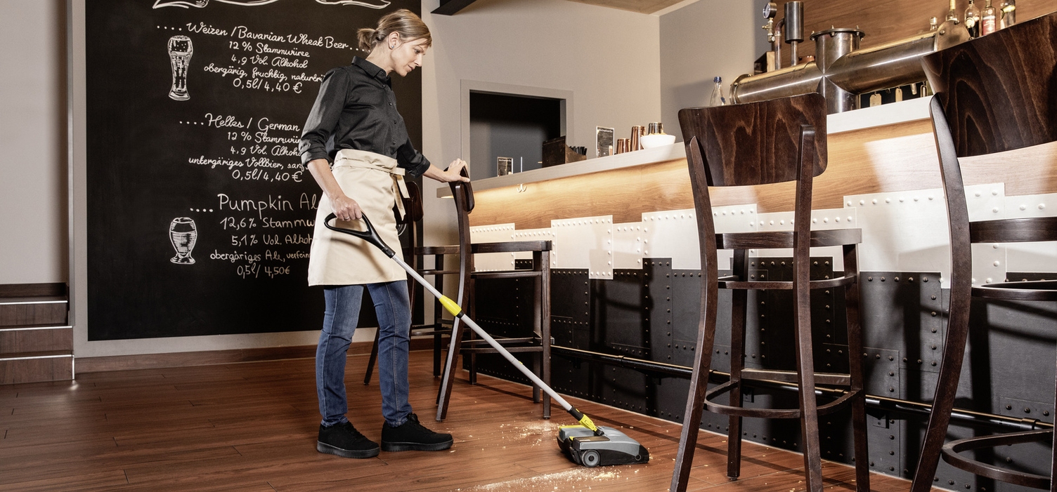 A person cleaning the floor with an electric broom