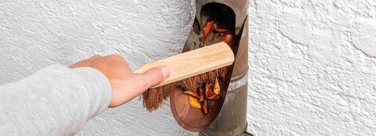 Removing leaves from a downpipe with a broom