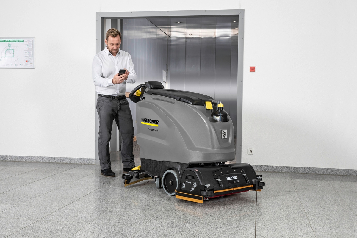 person using the service app next to a floor scrubber