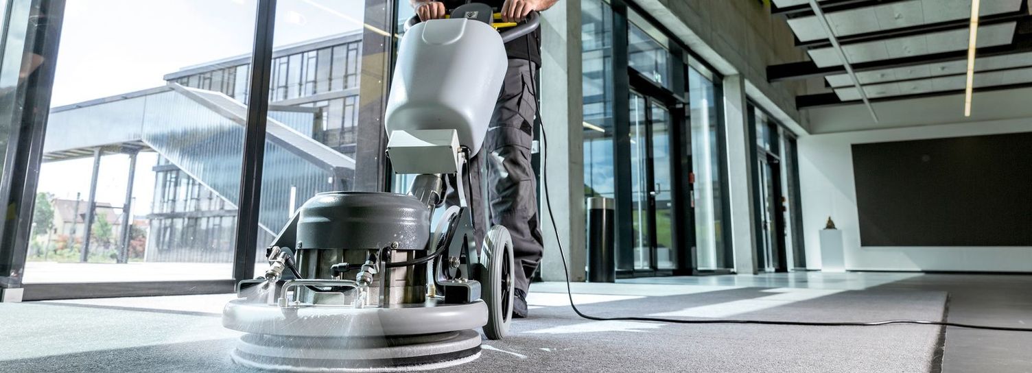 Deep carpet cleaning using the microfibre/yarnpad method A man cleans a hallway carpet with a Kärcher single disc machine