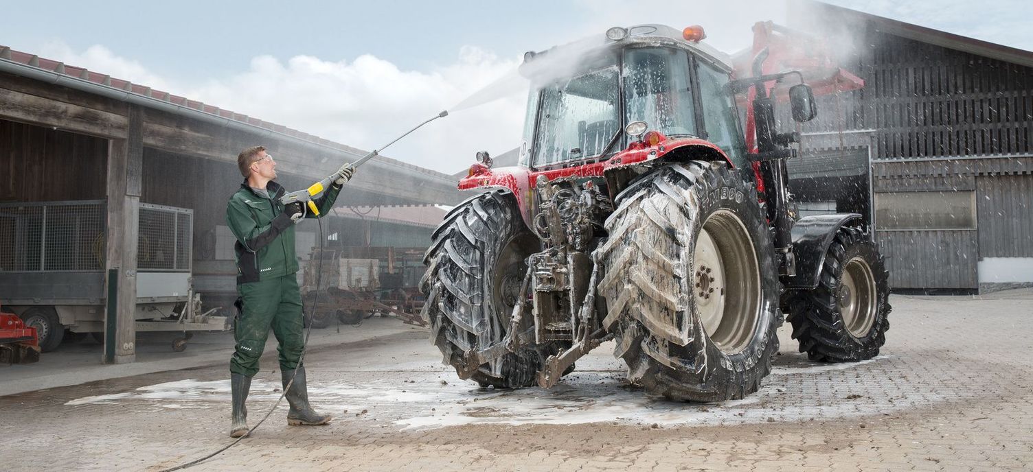 A man cleans his tractor with a Kärcher pressure washer