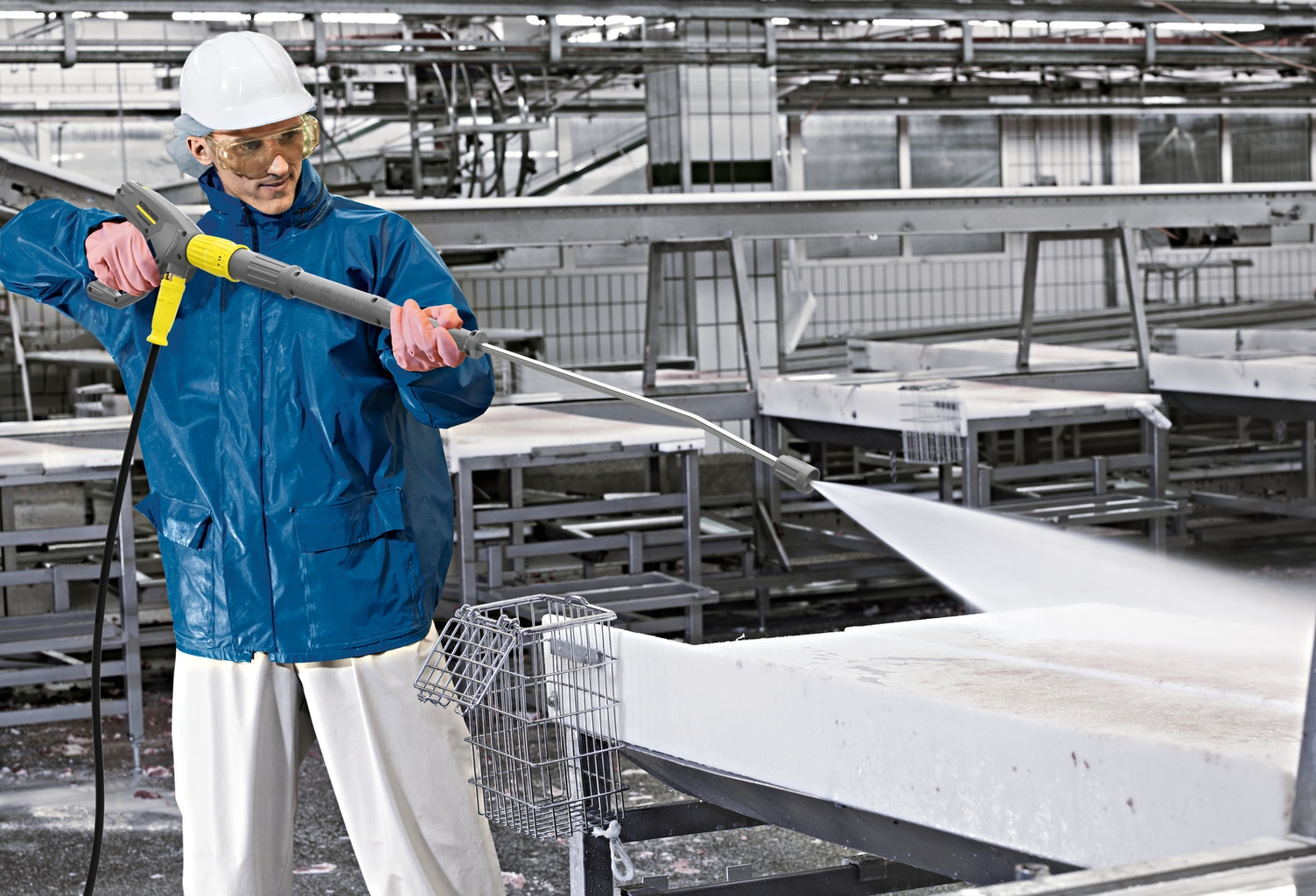 A man cleans a conveyor belt with a Kärcher pressure washer