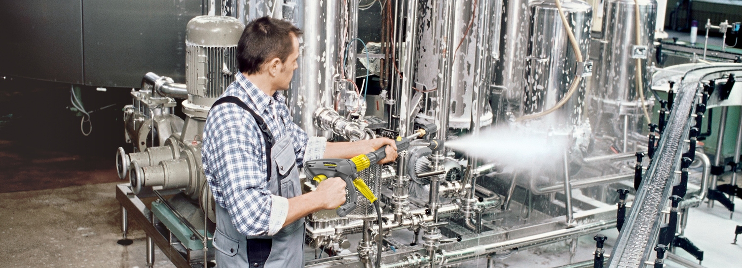 A man cleans the production area of a beverage industry with the help of a pressure washer
