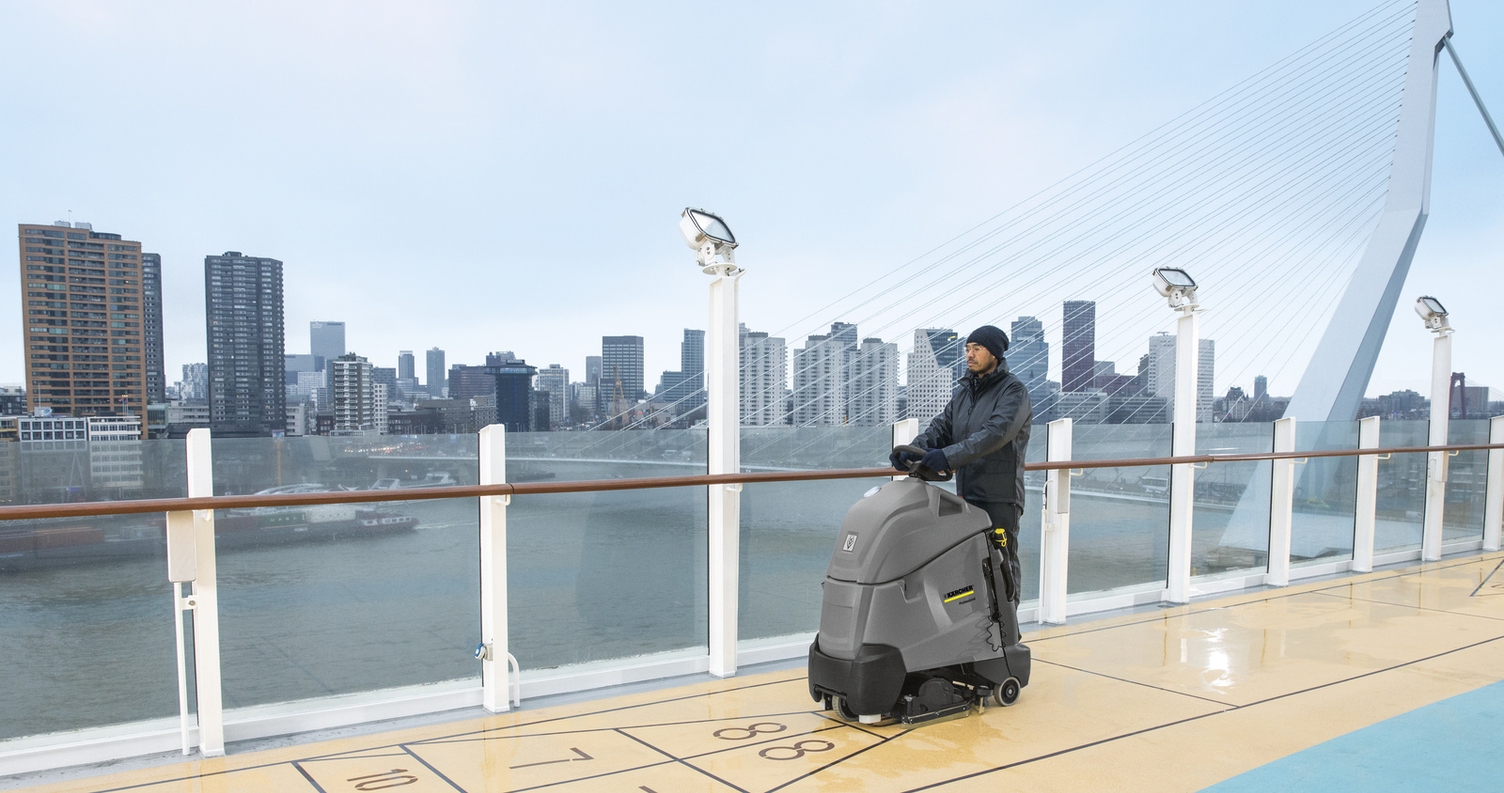 A person cleaning the deck of a cruise ship with a scrubber dryer