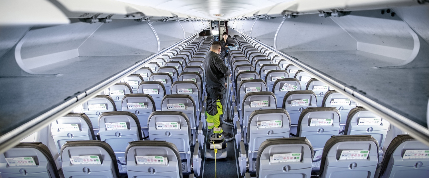 Two people cleaning the interior of an airplane