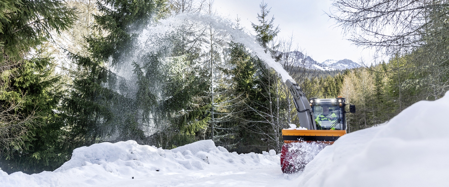 a snow blower clearing a snow-covered road in winter