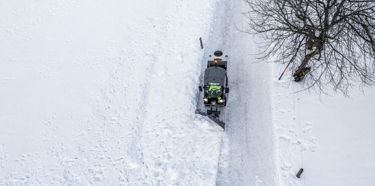 A Kärcher vehicle with articulated steering clearing a cycle path in winter