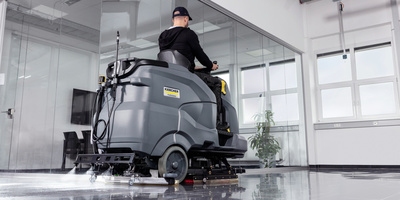 Person using the add-on for spray sanitation on a scrubber dryer