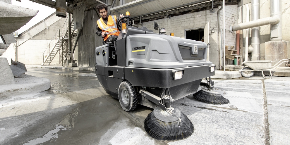 A man cleans the floor with a Kärcher industrial sweeper