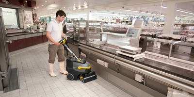 Person cleaning a supermarket floor with a Kärcher scrubber dryer Person cleaning a supermarket floor with a Kärcher scrubber dryer