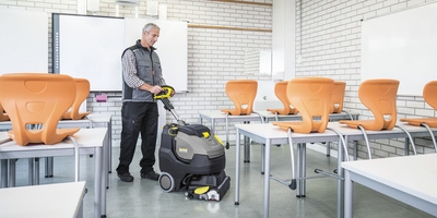 Person cleaning a class room with a scrubber dryer Person cleaning a class room with a scrubber dryer