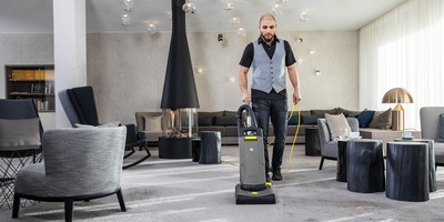 Person cleaning a hotel lobby with a vacuum cleaner