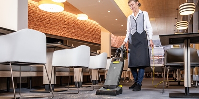 Person vacuum cleaning a restaurant Person vacuum cleaning a restaurant