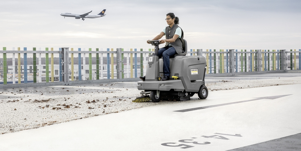 A person sitting on a Kärcher ride-on sweeper