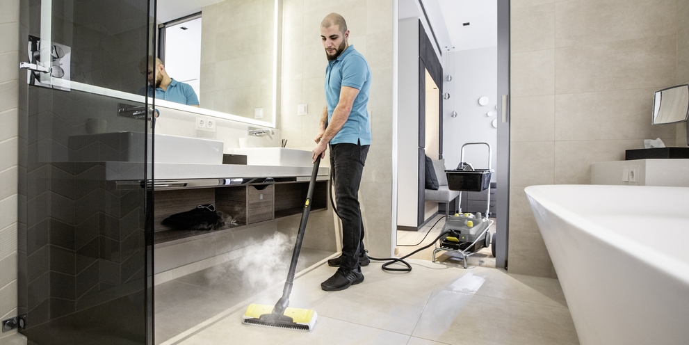 A person cleans the bathroom of a hotel room