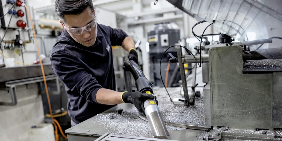 A man vacuums metal shavings with a mobile extraction unit