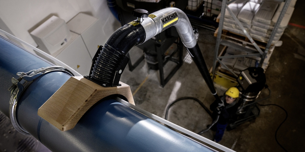 A person cleans a pipeline with the industrial vacuum cleaner with a telescopic tube