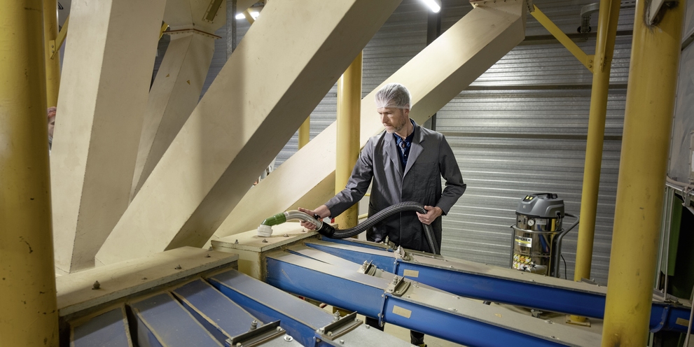 A man removes dust from surfaces with a Kärcher industrial vacuum cleaner