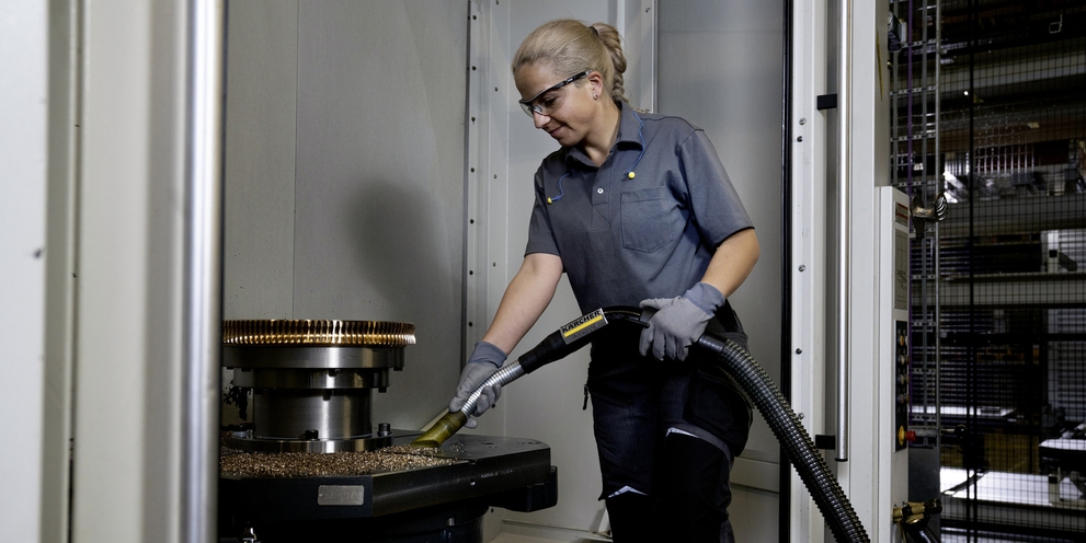 A woman vacuums greasy metal shavings