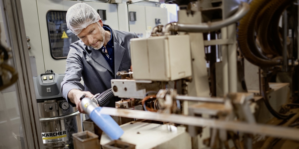 A man cleans a production facility with the industrial vacuum cleaner