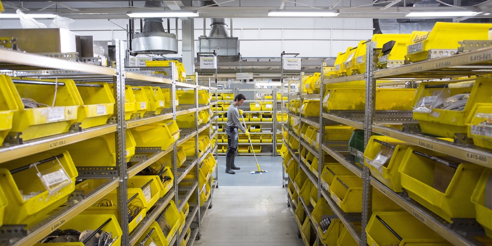 A man manually cleans the floor in the warehouse