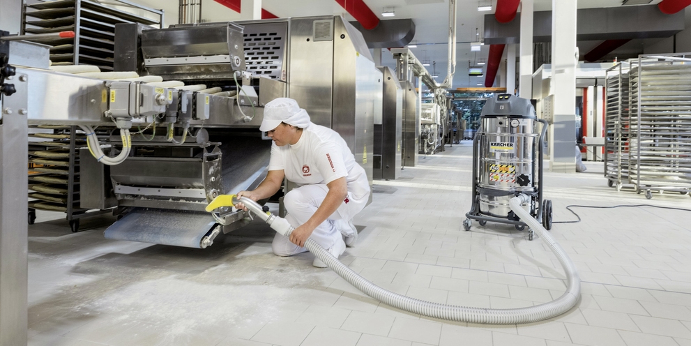 A person uses a Kärcher industrial vacuum cleaner for cleaning in the food industry