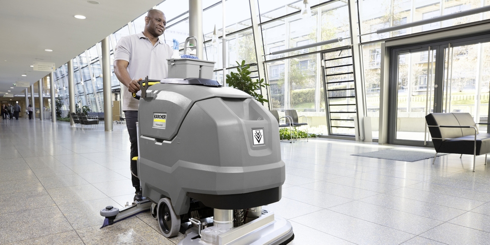 A person is operating a scrubber dryer in the entrance area